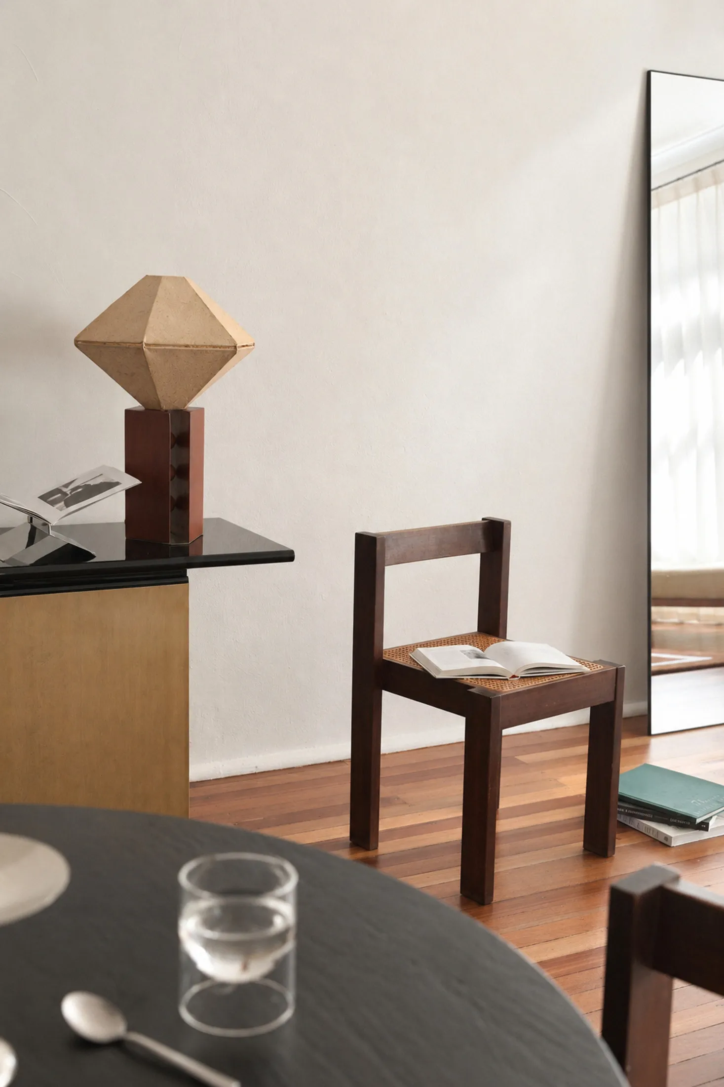 A sculptural lamp and timber chair beside a styled table